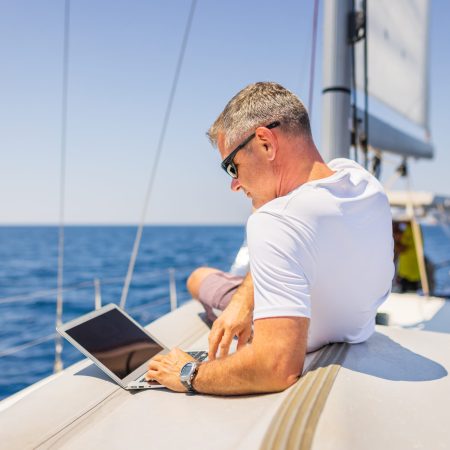 Businessman with laptop computer on sailboat.